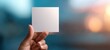 © Albi - The blank square note held between fingers against a colorful blurred bokeh background