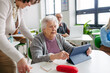© Halfpoint - Elderly woman learning digital skills with tutor help.