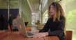 © Marco - Frustrated woman leaning back and pressing face with hands while sitting at laptop in modern office lounge, overwhelmed expression indicating work stress