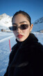 © OleksandrZastrozhnov - Asian female in sunglasses and black coat in snowy mountain scenery