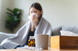 © Pormezz - Sick at home concept. Woman sneezing on the sofa in winter season.
