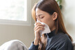 © Pormezz - Sick at home concept. Woman sneezing on the sofa in winter season.