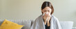 © Pormezz - Sick at home concept. Woman sneezing on the sofa in winter season.