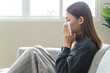 © Pormezz - Sick at home concept. Woman sneezing on the sofa in winter season.