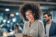 © Kowit - A smiling woman with curly hair interacts with a tablet in a modern workspace, creating a vibrant and engaging atmosphere.
