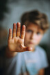 © SuperGlück - Child making a stop gesture while looking through a blurred background during a quiet afternoon indoors