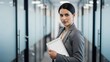 © photoplotnikov - Confident young asian female professional holding tablet in modern office hallway