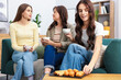 © New Africa - Friends with cups of drinks and treats on sofa at home