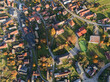 © AmazingAerialAgency - Aerial view of the charming village nestled among vibrant autumn foliage, with red-roofed buildings and winding roads creating a tapestry of color, Hrochot, Banska Bystrica Region, Slovakia.
