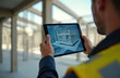 © Pete - Engineer in safety vest holds tablet computer. Device shows 3D building model overlaid on site. Pro inspects construction using digital tech. Analyzes plans for future development. Augmented reality