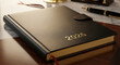 © Mirivox - Close-up of black textured planner with '2026' in gold, symbolizes future planning, organization, and setting goals on a desk with a pen, and gold object