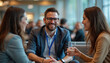 © Pete - Business people enjoy break during a conference. Smiling colleagues talking in cafe. Man wears glasses smiles. Woman holds drink. Teamwork conversation communication professional development.