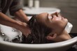 © Dina - Client relaxing in salon with hair being washed in ceramic sink, soft lighting enhancing calm atmosphere