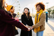 © Xavier Lorenzo - Group of young multi-ethnic people stacking hands, enjoying winter holidays together at amusement park