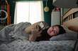 © Rob and Julia Campbell/Stocksy - Woman relaxing in bed holding smartphone in comfortably lit room