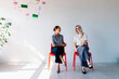 © OchreOchre/Stocksy - Two Women Sitting on Red Chairs Having a Friendly Conversation