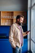 © OchreOchre/Stocksy - Man In Beige Jacket Looking At Smartphone By Window