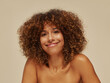 © Leandro Crespi/Stocksy - Smiling Woman With Curly Hair Against a Neutral Background