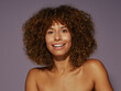 © Leandro Crespi/Stocksy - Smiling Woman With Curly Hair Against a Purple Background