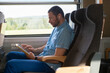 © Jelena Jojic Tomic/Stocksy - Man Reading on a Train using a tablet and earbuds