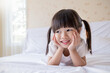 © paulaphoto - Portrait adorable little girl with pigtails smile brightly while lying on a white bed in a cozy cheerful home environment. Education preschool toddler.