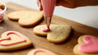 © vstudio - Decorating heart shaped cookies with pink icing for Valentine's Day sweet treats and baking fun