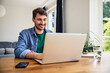 © baranq - Successful young man using laptop working at home freelancing remotely