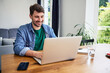 © baranq - Young happy freelancer using laptop working at home