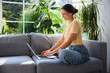 © baranq - young woman using laptop at home sitting on sofa