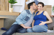 © auremar - man kissing his pregnant wife on couch