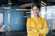 © Tetiana - Portrait of a young Indian businesswoman in a yellow shirt with her arms crossed on her chest standing in the office and looking confidently at the camera