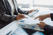 © Crystal - Business professionals collaborating, sharing insights, and analyzing financial graphs with a calculator on an office desk