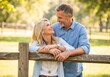 © Vasiliy - Happy mature couple in love smiling at each other outdoors. Affectionate middle-aged man and woman enjoying a romantic moment in a park