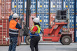 © reewungjunerr - Back view of diverse engineers supervising forklift at shipping yard. Asian foreman signaling and black woman with radio controlling container logistics. Industrial teamwork concept.
