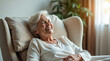 © miss irine - Happy senior woman laughs heartily while relaxing in a cozy armchair at home. She enjoys comfort and leisure in a bright room, breathing fresh air. This moment captures pure joy and contentment.