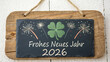 © DND - Wooden hang tag and slate with four leaf clover and sparklers with the german words for happy new year - frohes neues jahr 2026 on wooden weathered background