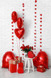 © Pixel-Shot - Heart shaped air balloons with gift boxes and bouquet of red roses near white brick wall. Valentine's day celebration
