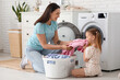 © Pixel-Shot - Young woman and her little daughter doing laundry at home