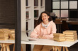 © Pixel-Shot - Female student sitting at table with laptop and stack of books in library