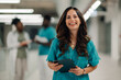 © Zamrznuti tonovi - Smiling medical professional holding tablet standing in hospital corridor