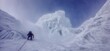 © Aquir - Climber trekking icy mountain ridge through dense fog. Solo mountaineer navigating a challenging snowy ridge against a foggy sky