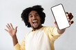 © Prostock-studio - An enthusiastic African American man joyfully presents a smartphone with a blank screen, creating a welcoming space for application or website design.