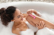 © Prostock-studio - Relaxing in a bubble bath, a woman shaves her legs with a pink razor. She enjoys her time in a serene bathroom. The atmosphere is peaceful and calming.