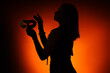 © Pixel-Shot - Silhouette of beautiful young woman with carnival mask on orange background