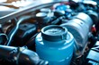 © juliars - Blue windshield washer fluid reservoir stands out against the complex background of a car engine, highlighting regular maintenance