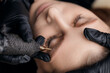 © Parilov - Young caucasian female receiving eyebrow microblading permanent treatment by professional, top view