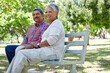 © peopleimages.com - Senior couple, thinking and bonding with park bench for sightseeing, comfort or outdoor fresh air. Elderly, man and woman with smile or love for holiday, weekend or retirement together in nature