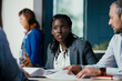 © Suteren Studio - Black Female Manager Providing Feedback to Junior Employee in Multicultural Office