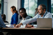 © Suteren Studio - Smiling Black Woman Leading Feedback Session Meeting in Modern Open Office