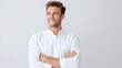 © pkproject - A smiling confident young man with blue eyes and neat hair wearing a white button up shirt with arms crossed posing for a professional portrait in a studio with a neutral background